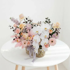 Bunga segar dalam keranjang anyaman dengan orkid putih dan mawar pastel, online florist terpercaya