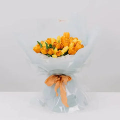 Buket bunga tulip kuning segar dari online florist, dibungkus kertas transparan dengan pita oranye