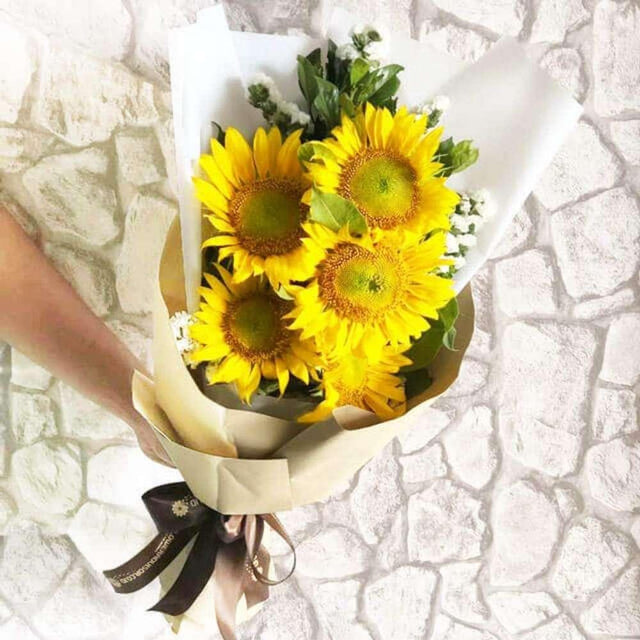 Buket bunga matahari segar dari online florist, dikemas rapi dengan pita cokelat, ideal untuk hadiah.