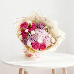Bouquet bunga mawar merah muda dan ungu dari online florist, dikemas elegan dengan pita pink.