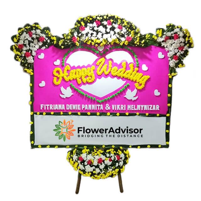 Bunga papan pernikahan 'Happy Wedding' dari online florist, hiasan bunga warna-warni untuk pasangan pengantin.