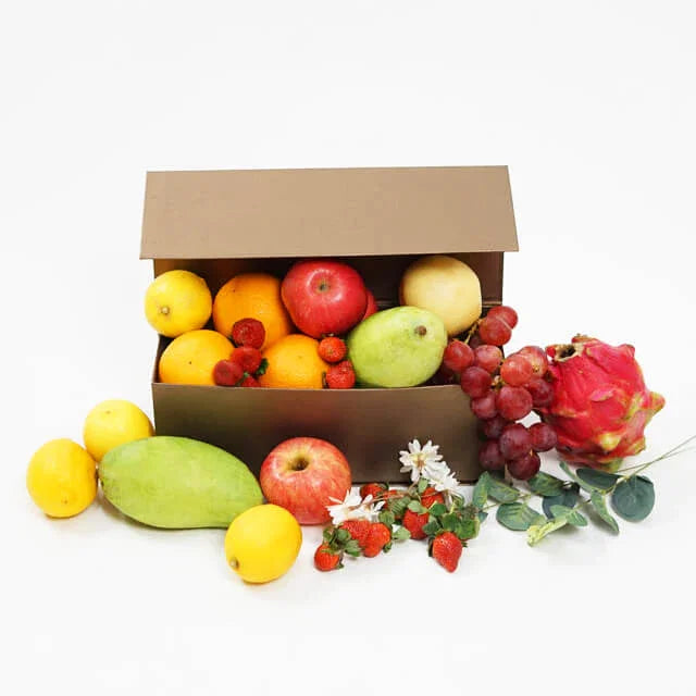Kotak buah segar dengan apel, jeruk, stroberi, anggur, dan buah naga, disertai bunga kecil — online florist