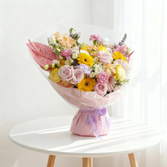 Buket bunga warna-warni cantik dari online florist, dikemas rapi dengan pita ungu, cocok untuk hadiah istimewa.