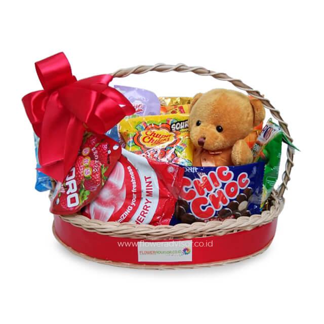 Keranjang hadiah online florist berisi boneka beruang, permen, dan cokelat dengan pita merah
