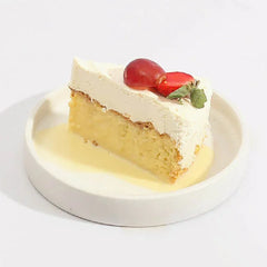 Potongan kue keju lembut dengan krim putih dan buah merah, disajikan di piring putih. Online florist.