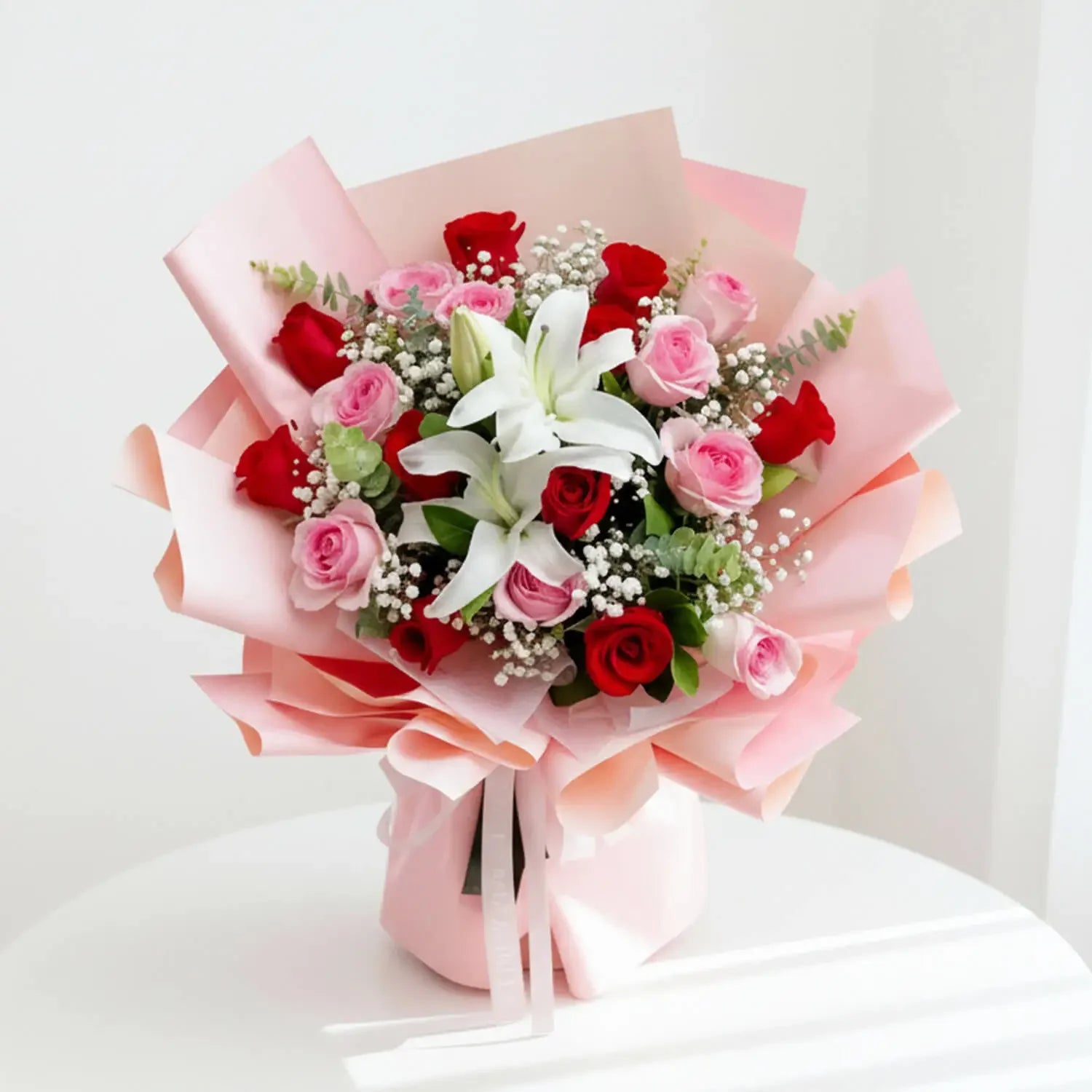 Buket bunga mawar merah dan pink dengan lili putih, dibungkus kertas pink, dari online florist