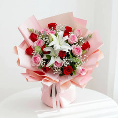 Buket bunga mawar merah dan pink dengan lili putih, dibungkus kertas pink, dari online florist