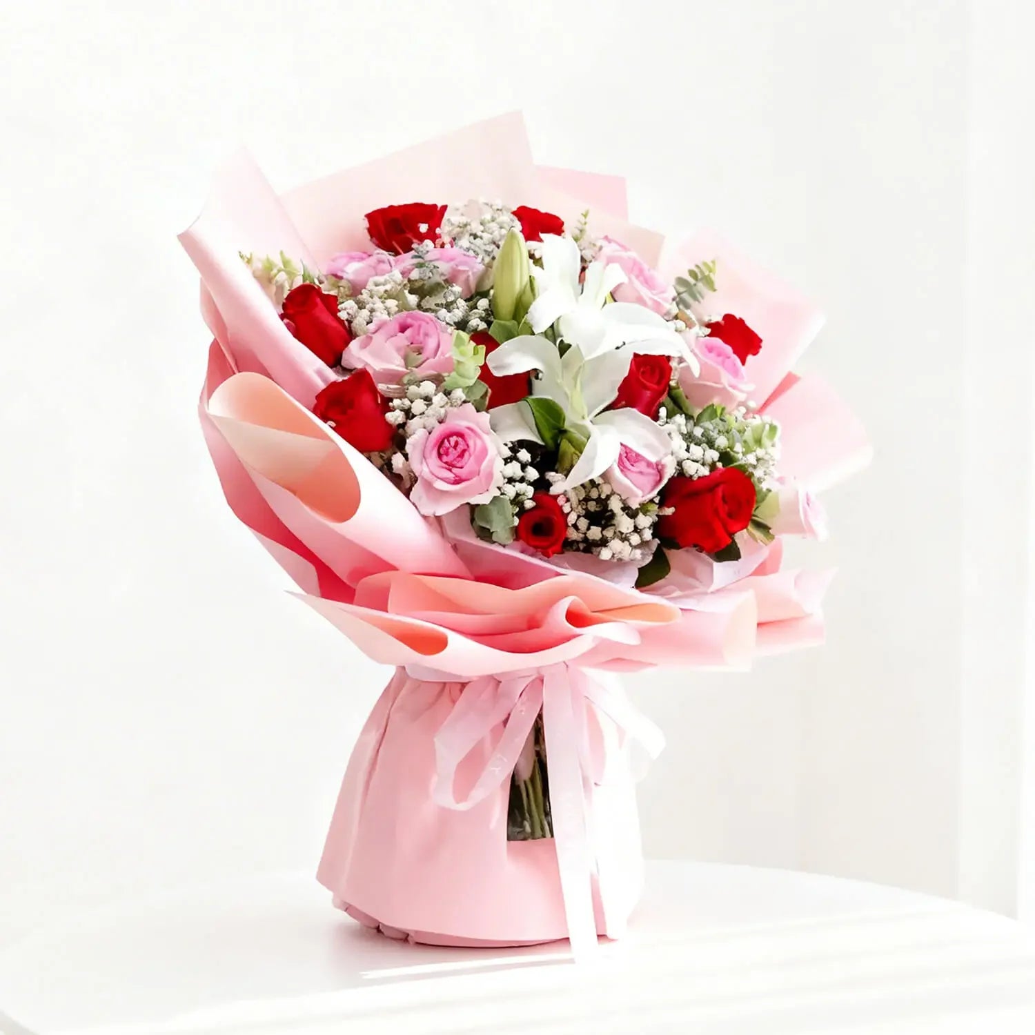 Buket bunga mawar merah dan pink dengan lili putih, dibungkus kertas pink, dari online florist