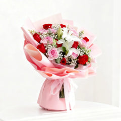 Buket bunga mawar merah dan pink dengan lili putih, dibungkus kertas pink, dari online florist