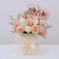Floral arrangement in a box with pink balloons on a white background