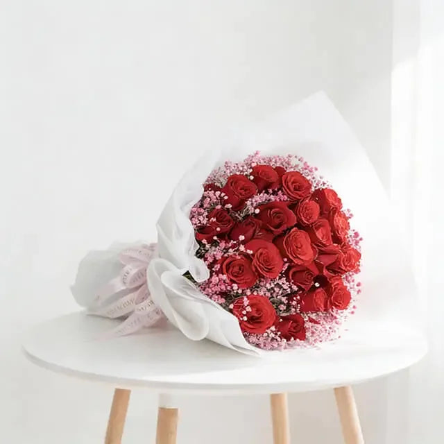 Buket bunga mawar merah segar dari online florist, dibungkus kertas putih dan pita pink, siap dikirim.