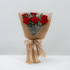 Buket bunga mawar merah elegan dari online florist, dibungkus kertas craft dengan pita satin