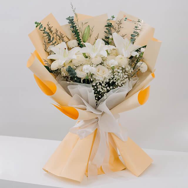 Buket bunga putih elegan dengan lili dan mawar, dibungkus kertas krem dan pita, online florist