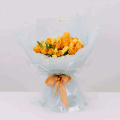 Buket tulip kuning dan oranye dari online florist, dibungkus kertas biru muda dengan pita oranye
