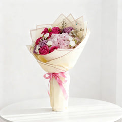 Buket bunga mawar merah muda dan ungu dari online florist, dibungkus kertas krem dengan pita pink