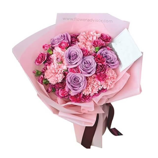 Bouquet bunga mawar ungu dan karnasi pink dari online florist, dikemas cantik dengan pita cokelat.