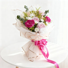 Buket bunga mawar pink dan putih elegan dari online florist, dibungkus kertas cantik dengan pita merah muda.