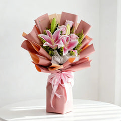 Buket bunga mawar dan lili pink elegan dari online florist, dibungkus kertas warna pastel dengan pita cantik.