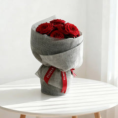 Bouquet mawar merah elegan dari online florist, dibungkus kain abu-abu dengan pita merah