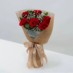 Buket bunga mawar merah elegan dari online florist, dibungkus kertas craft dengan pita cantik