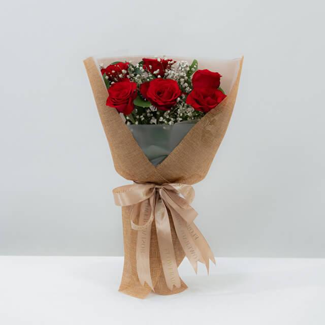 Buket bunga mawar merah elegan dari online florist, dibungkus kertas craft dengan pita satin